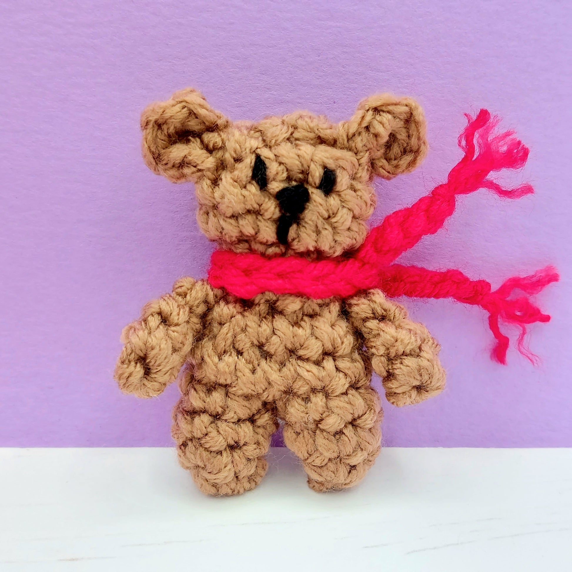 Small crochet teddy bear with red scarf